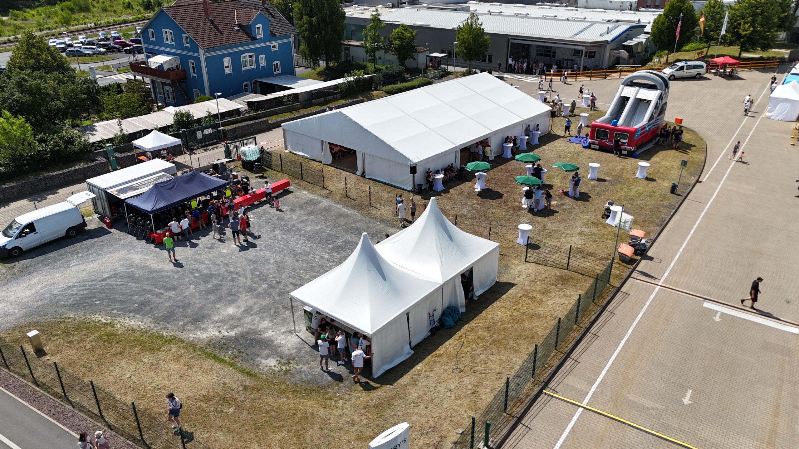 Firmen-Sommerfest von oben mit Zelten, Sonnenschirmen und Gästen