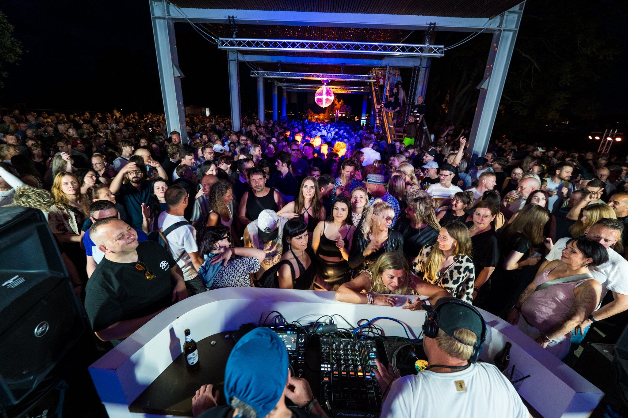 Volle Tanzfläche vor dem DJ-Pult bei einem Open-Air-Event