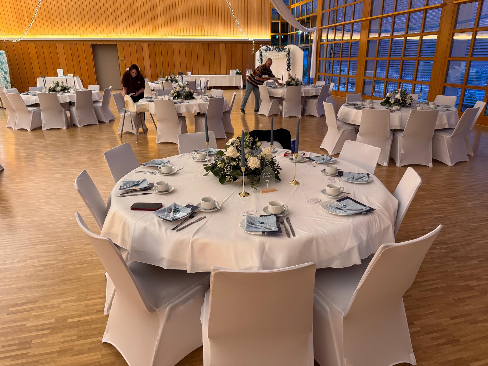 Gedeckter runder Tisch mit Blumen in einem Festsaal