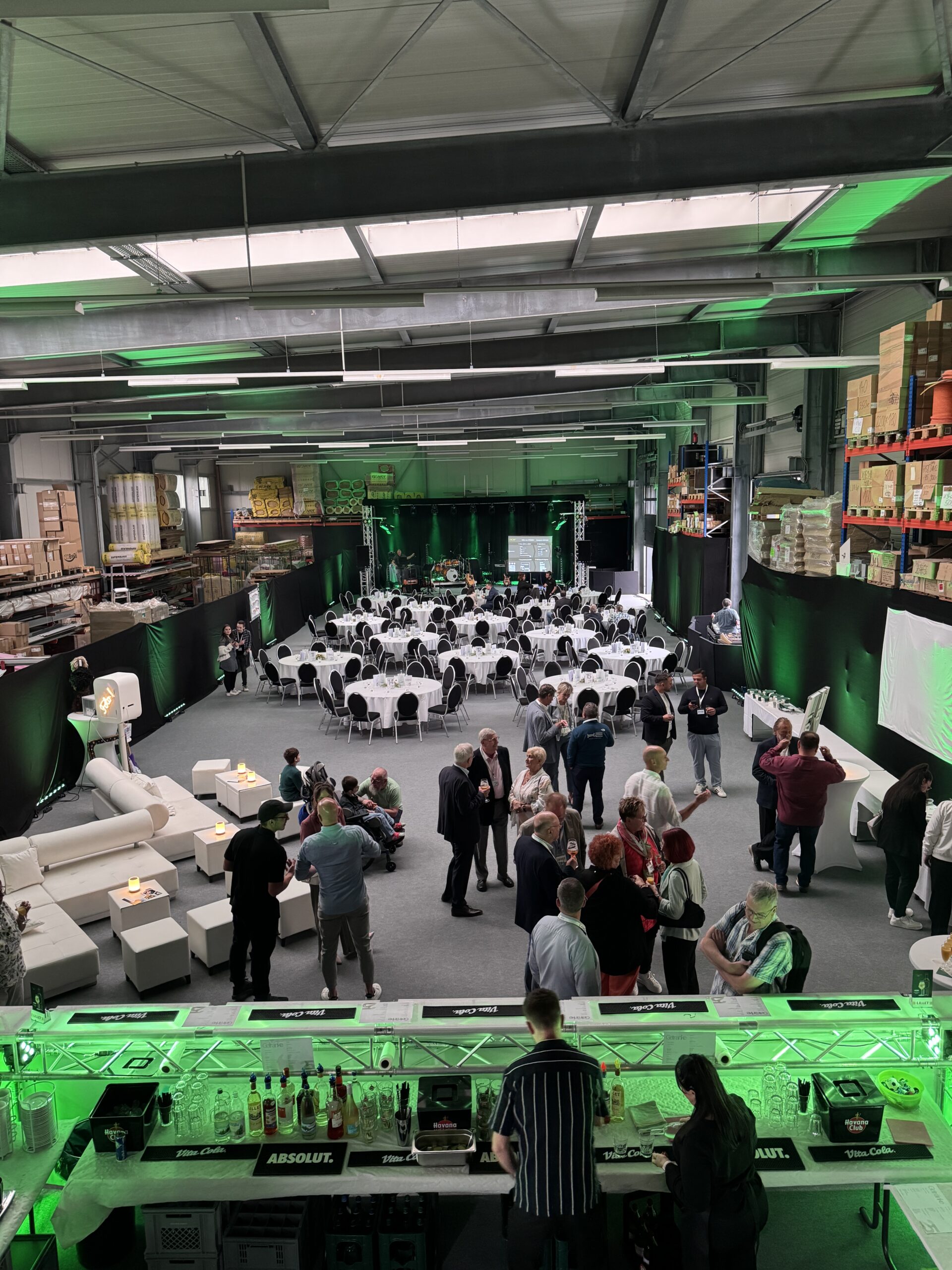Firmenjubiläum in einer Halle mit Lounge, Bar, Tafeln und Bühne