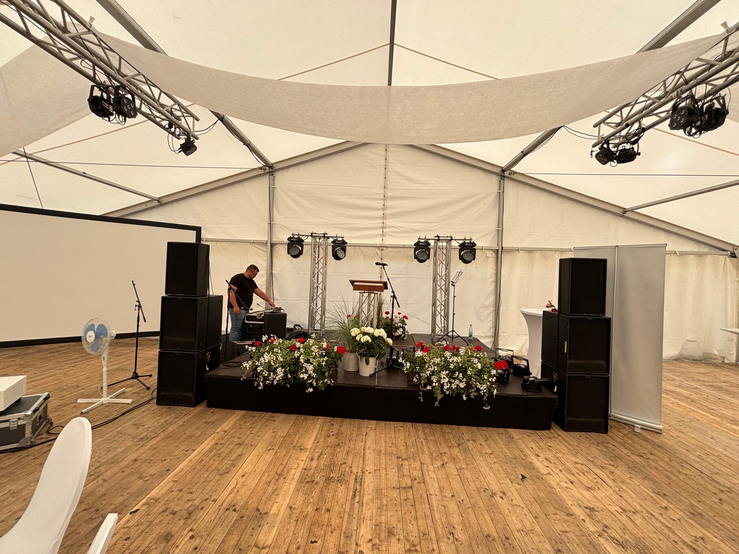 Bühne mit Tontechnik und Blumen in einem Festzelt