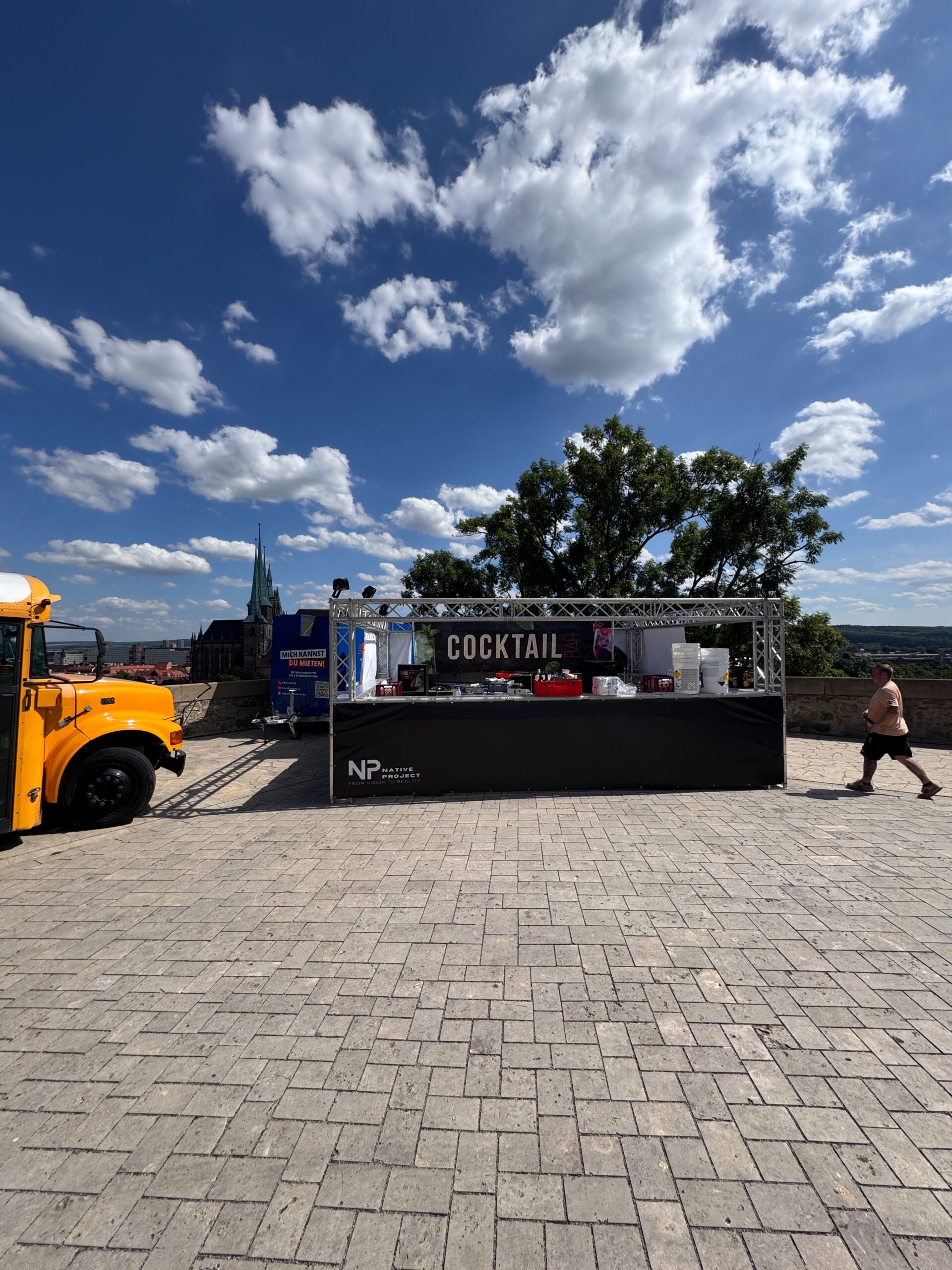 Mobile Cocktailbar mit Traversen und Native-Project-Logo unter blauem Himmel