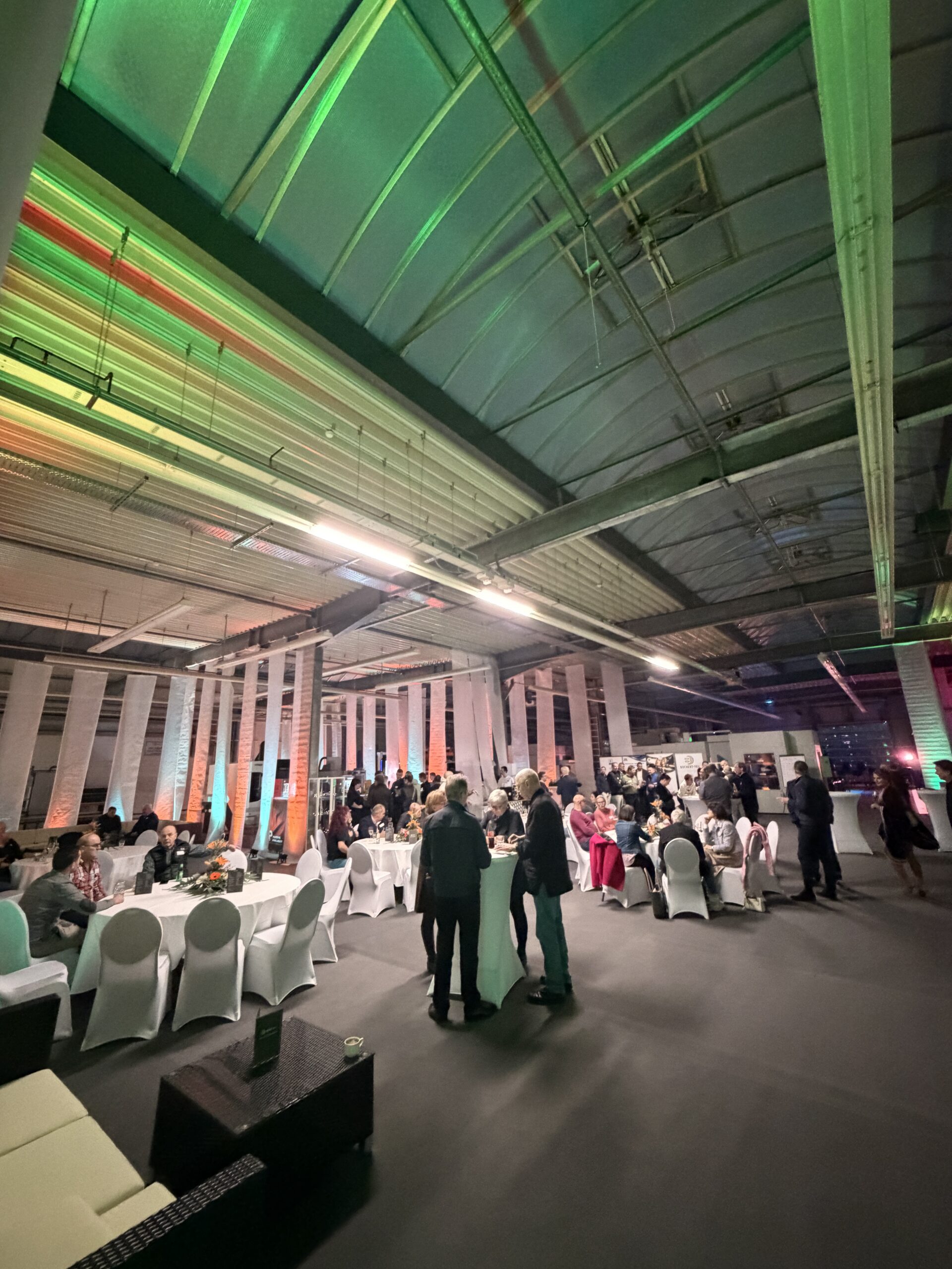 Halle mit Deckenstoffen, farbigem Licht, Tafeln und Gästen