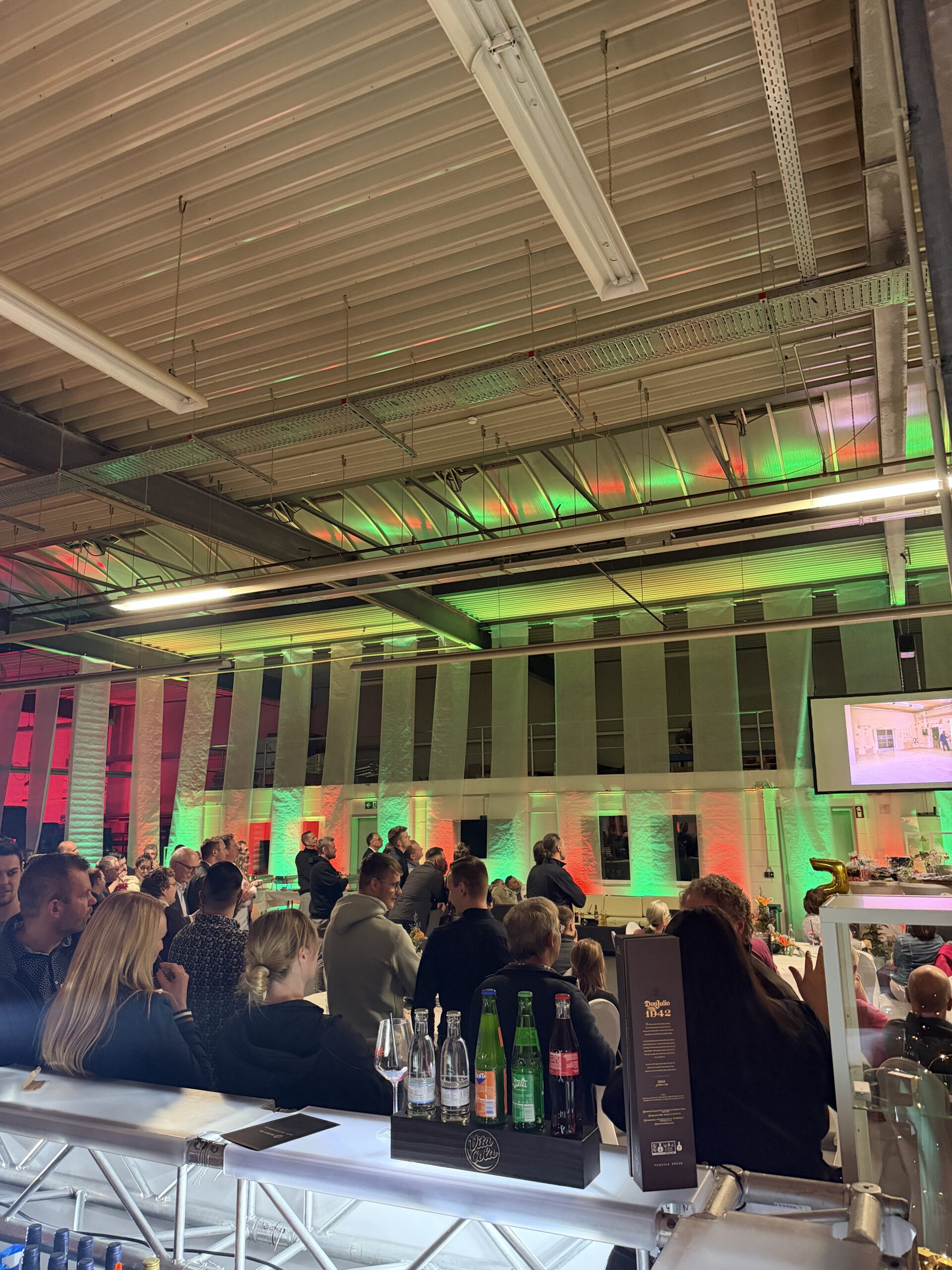 Gäste feiern in einer Halle mit grünem und rotem Licht