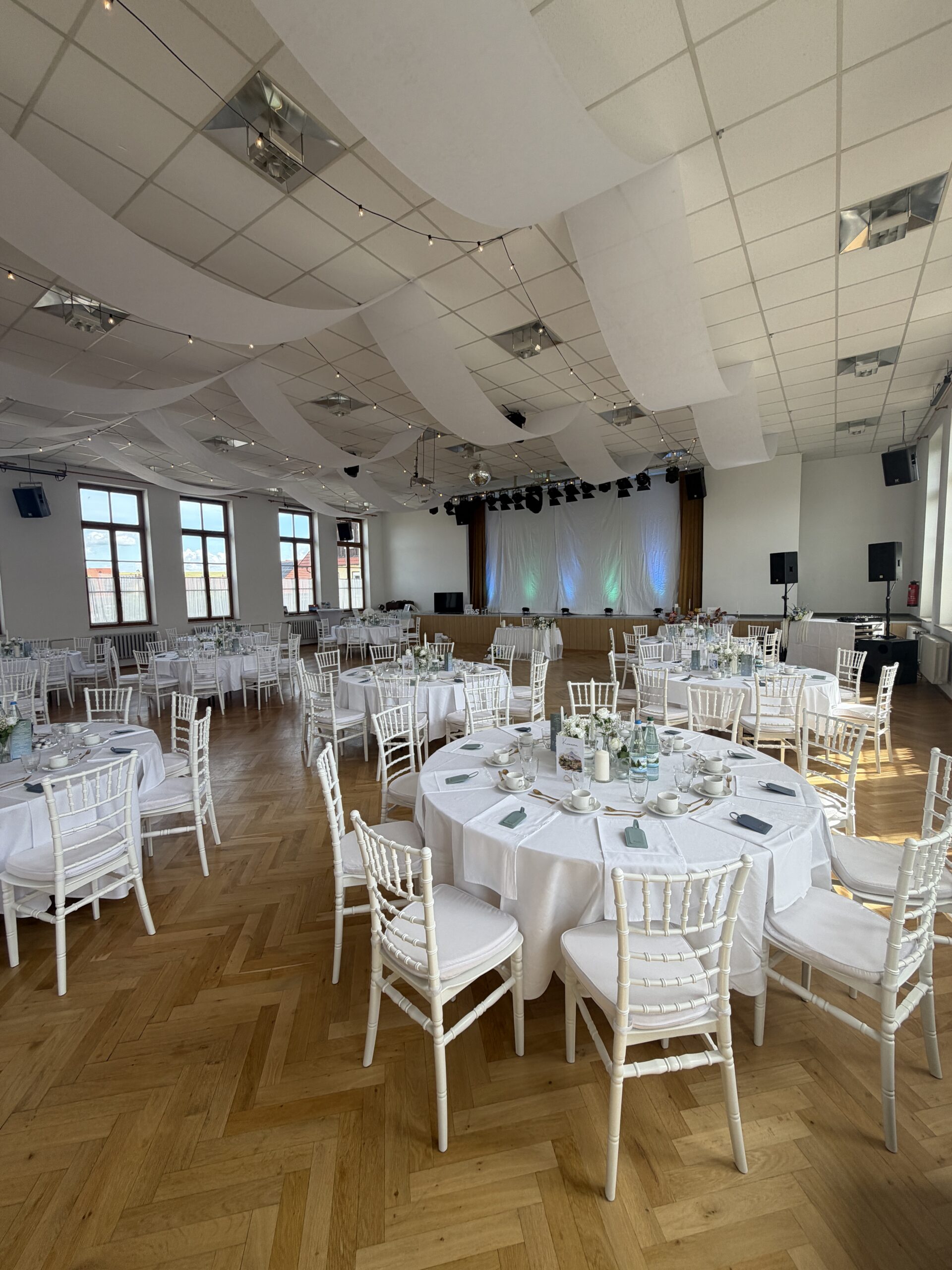 Festsaal mit runden Tafeln und weißen Chiavari-Stühlen