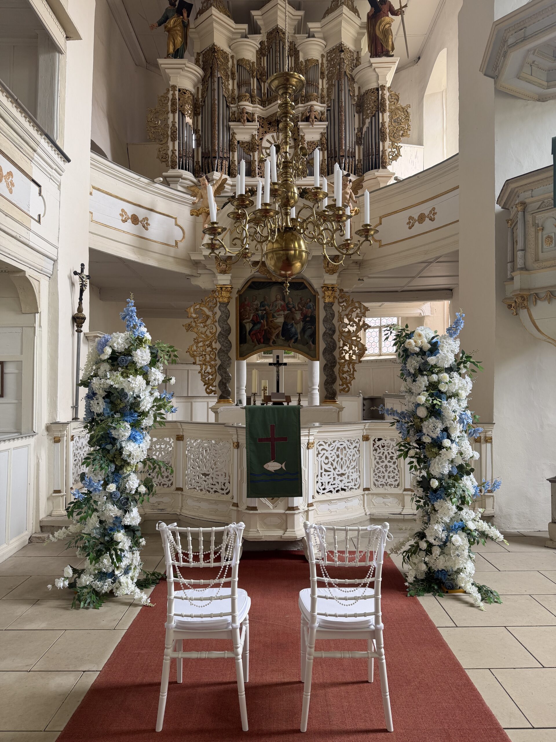 Kirche mit Blumenbögen und weißen Stühlen zur Trauung