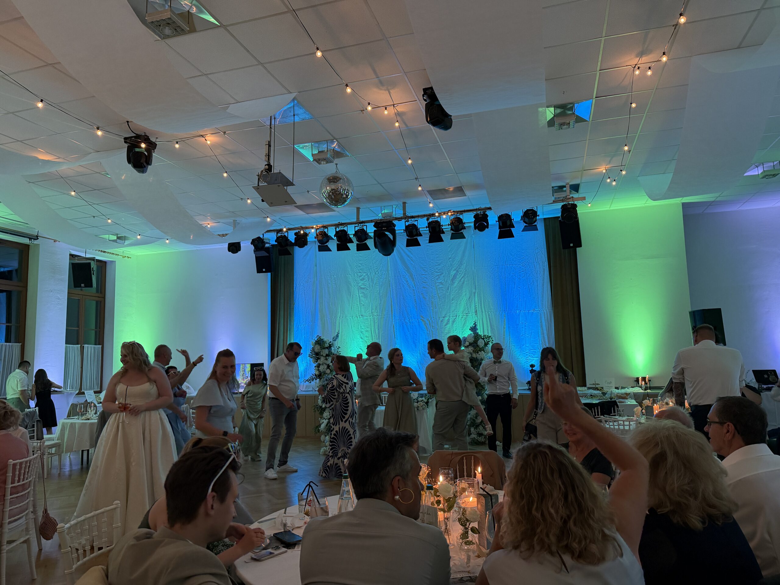 Hochzeitsgesellschaft feiert im Saal mit grünem und blauem Licht