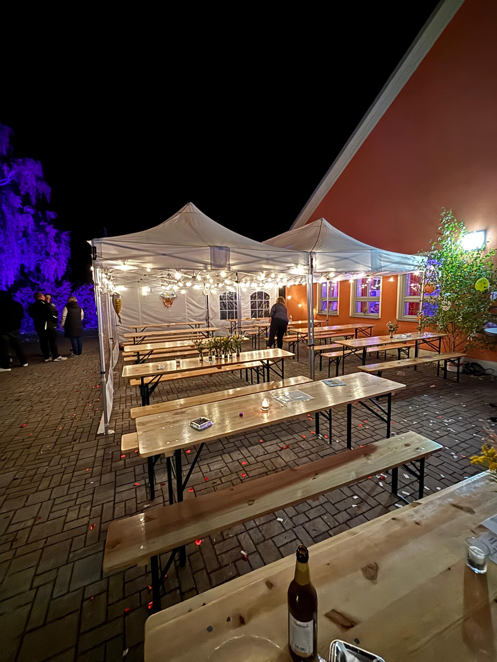 Pavillons mit Festzeltgarnituren und Lichterketten am Abend