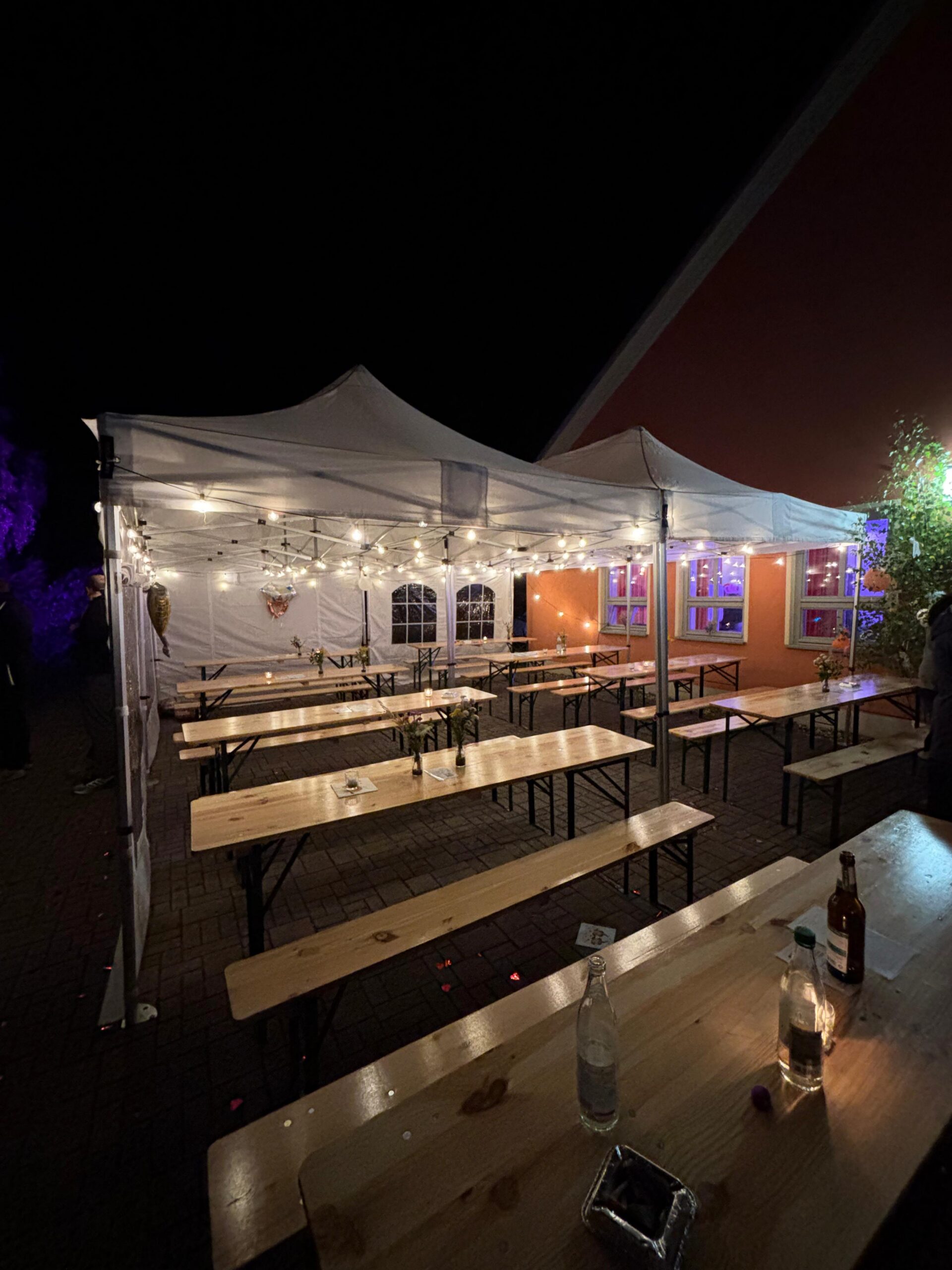 Pavillons mit Festzeltgarnituren und Lichterketten am Abend