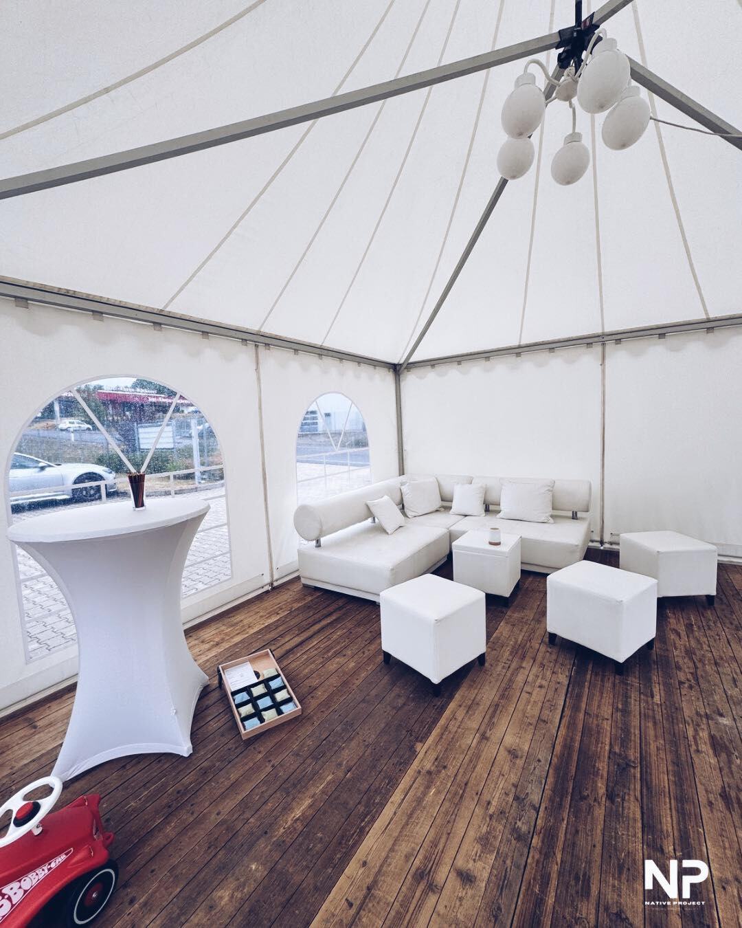 Loungebereich mit weißen Sitzmöbeln und Stehtischen im Zelt
