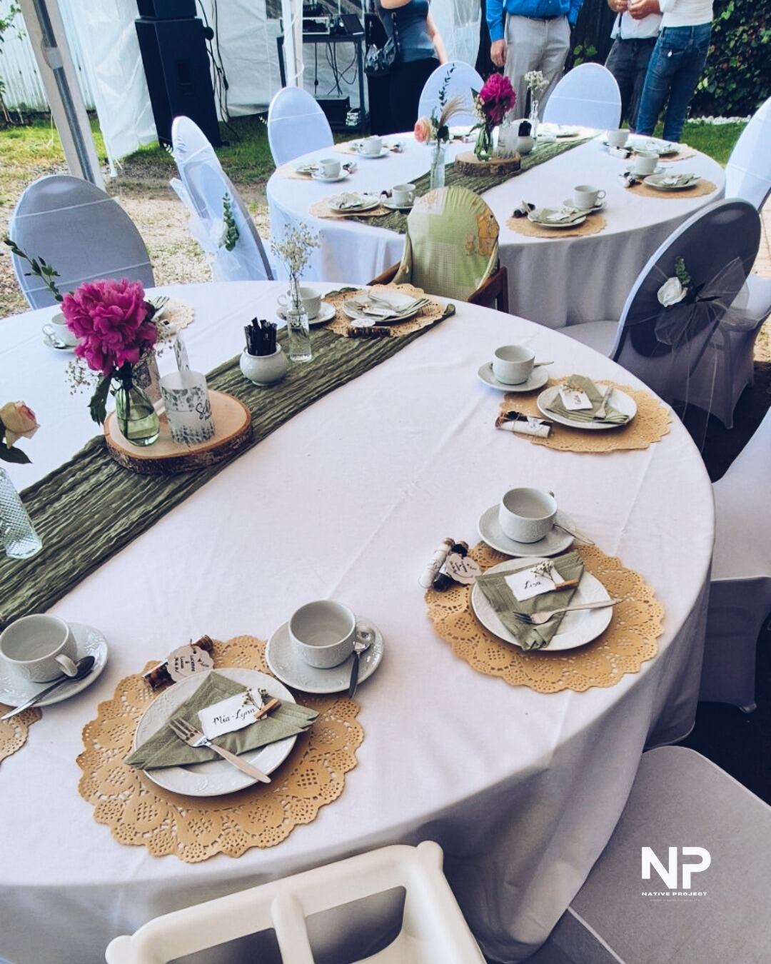 Lange Tafel mit Tischläufer, Gedecken und Blumenschmuck im Garten