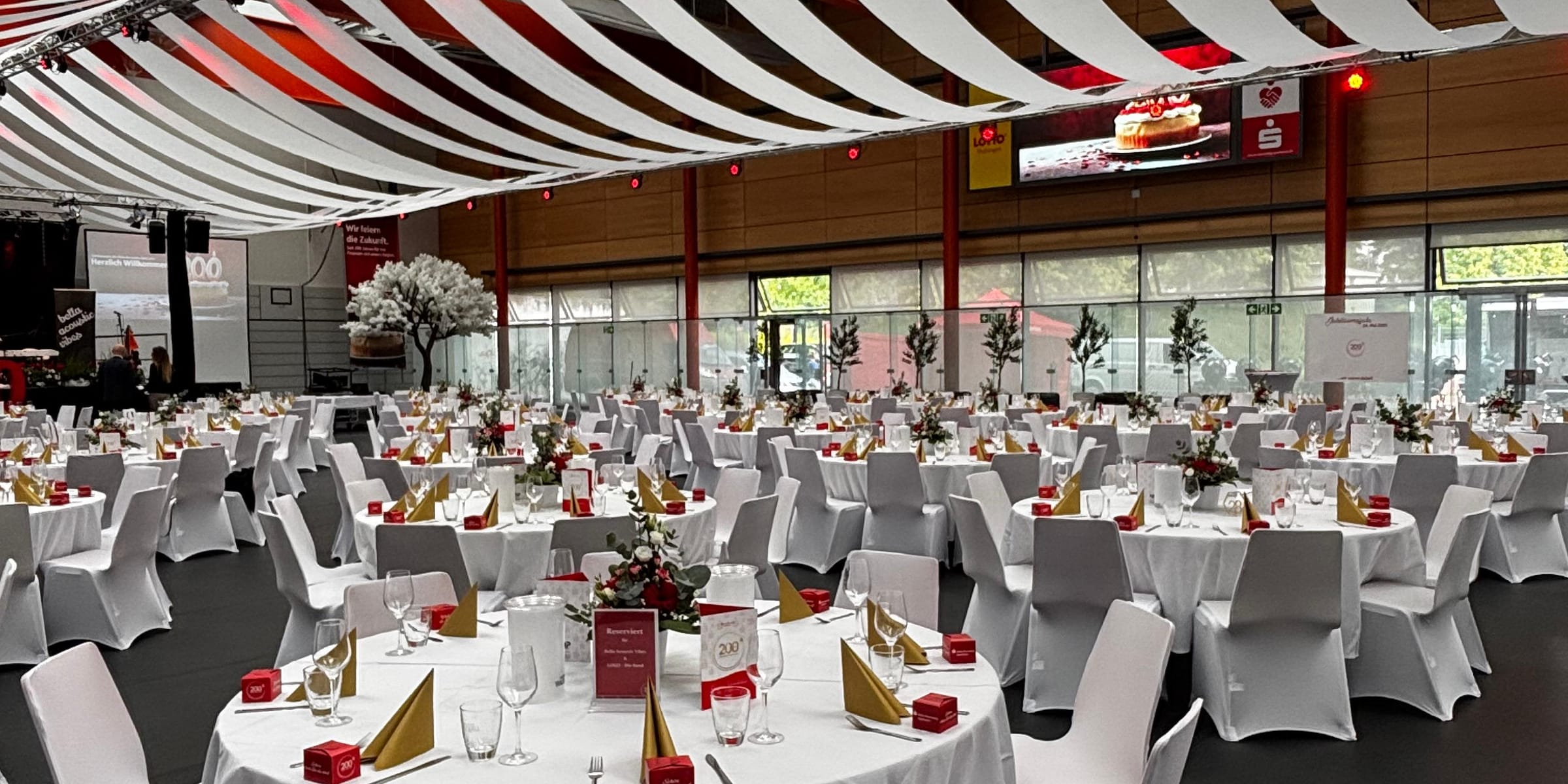 Gala-Saal mit runden Tafeln, Stuhlhussen und Deckenbahnen